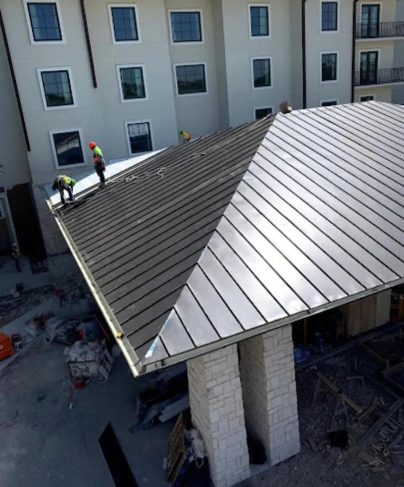 Crew installing standing seam metal roof panels on a commercial project in Spout Springs